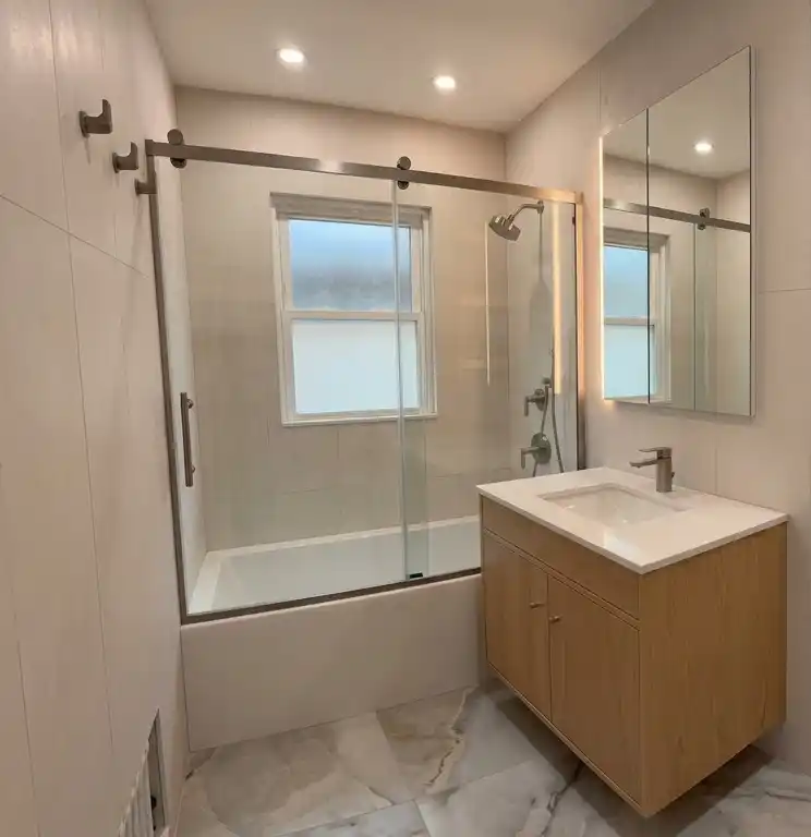 This modern bathroom remodel incorporated high-end finishes and thoughtful design choices to create a sleek and functional space. The project involved the installation of a new lighted medicine cabinet, a custom tub/shower, frame-out built-in shelving, and a japanese smart toilet, making the bathroom both elegant and highly practical | Batroom Remodel | East 21 Street, Brooklyn NY | DCON Renovations New York - Brooklyn | Remodeling - Architectural Design - Residential Contractor - Brownstoner Experts
