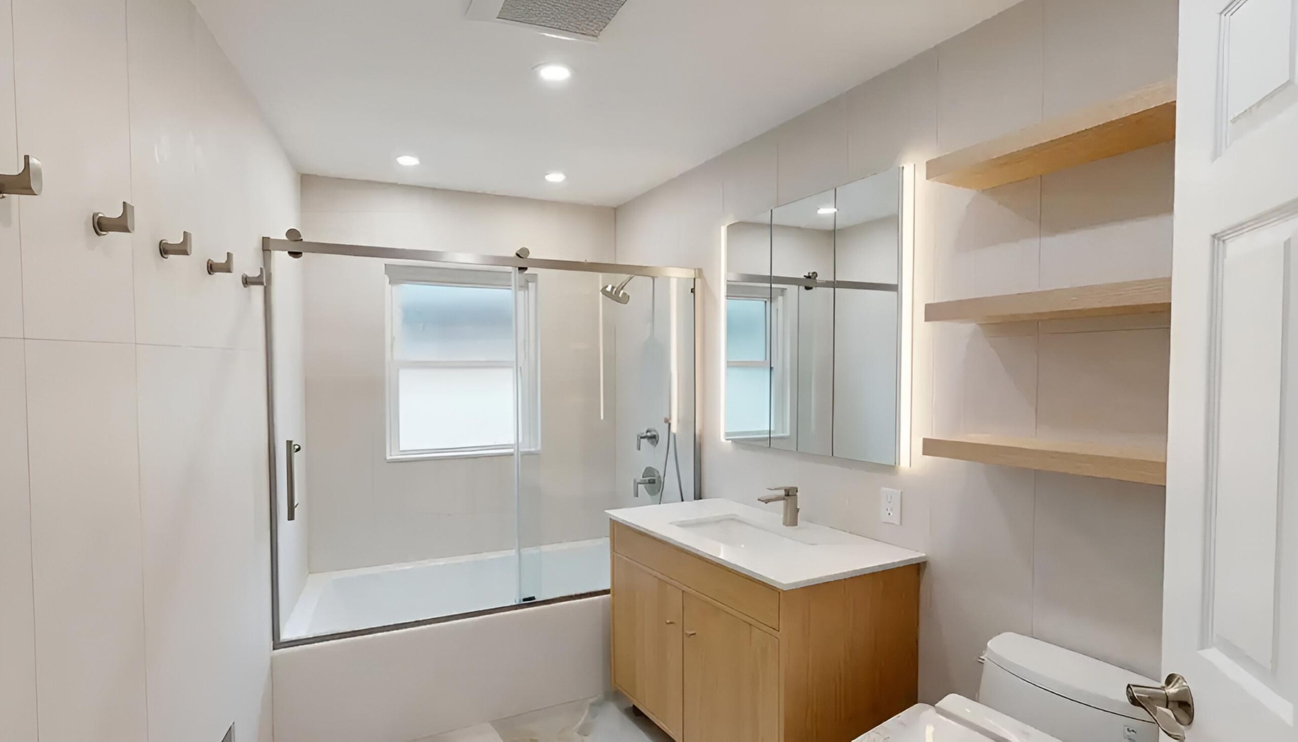 This modern bathroom remodel incorporated high-end finishes and thoughtful design choices to create a sleek and functional space. The project involved the installation of a new lighted medicine cabinet, a custom tub/shower, frame-out built-in shelving, and a japanese smart toilet, making the bathroom both elegant and highly practical | Batroom Remodel | East 21 Street, Brooklyn NY | DCON Renovations New York - Brooklyn | Remodeling - Architectural Design - Residential Contractor - Brownstoner Experts